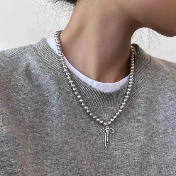 Collier de perles grises et nœud argenté