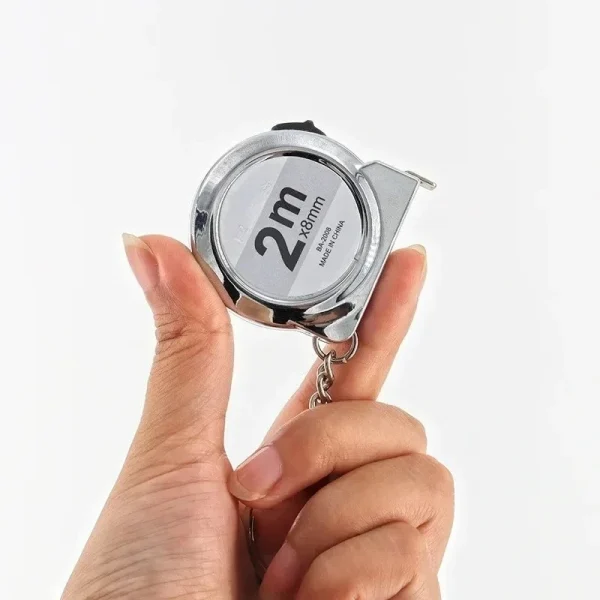 Mini mètre ruban argenté tenu en main